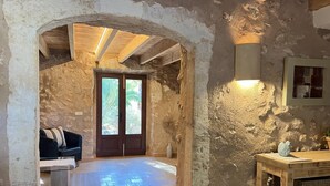 A rustic stone interior with a wooden door, a cushioned seating area, and a small table. - CAN PINA - ECO PINA - Apartment with shared pool in Costitx. Free WiFi (Costitx)