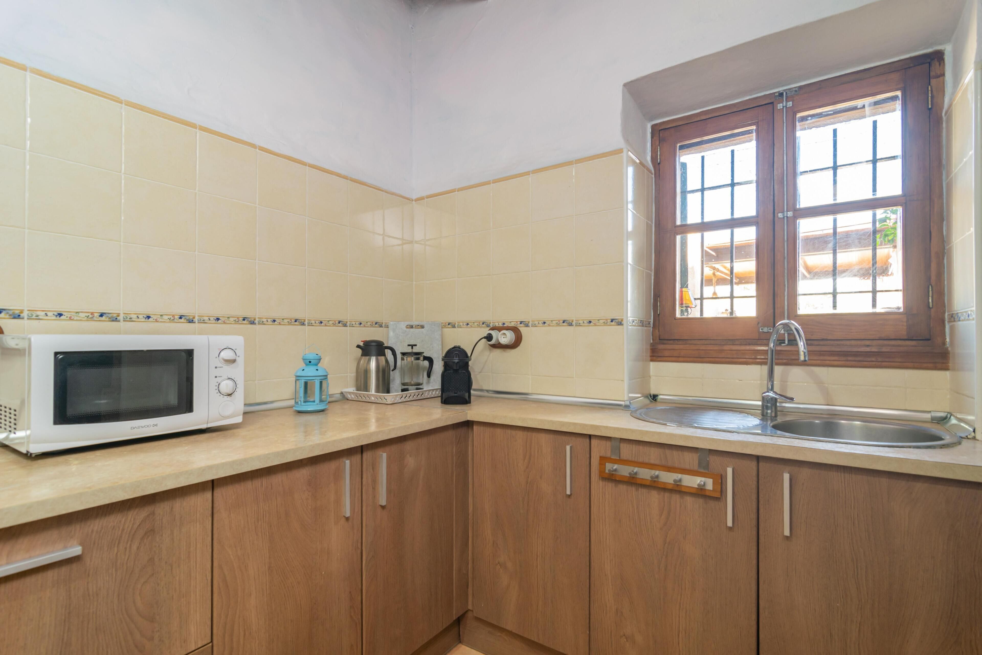 A kitchen with a microwave, coffee maker, and a window with a sink.