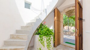 Eine Treppe mit einem Blumenkasten mit Grünpflanzen, einer Holztür und einer Steinwand im Hintergrund.