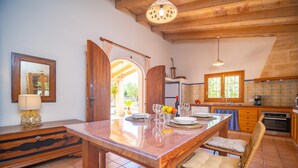 Una cucina con isola in legno, un tavolo da pranzo, sedie e vista tramite un arco aperto.