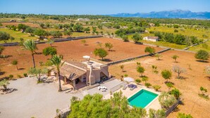 Una villa con piscina, circondata da alberi e vista su montagne lontane.