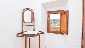 A bathroom with a wooden chair, a small window, and a view of a rural landscape.