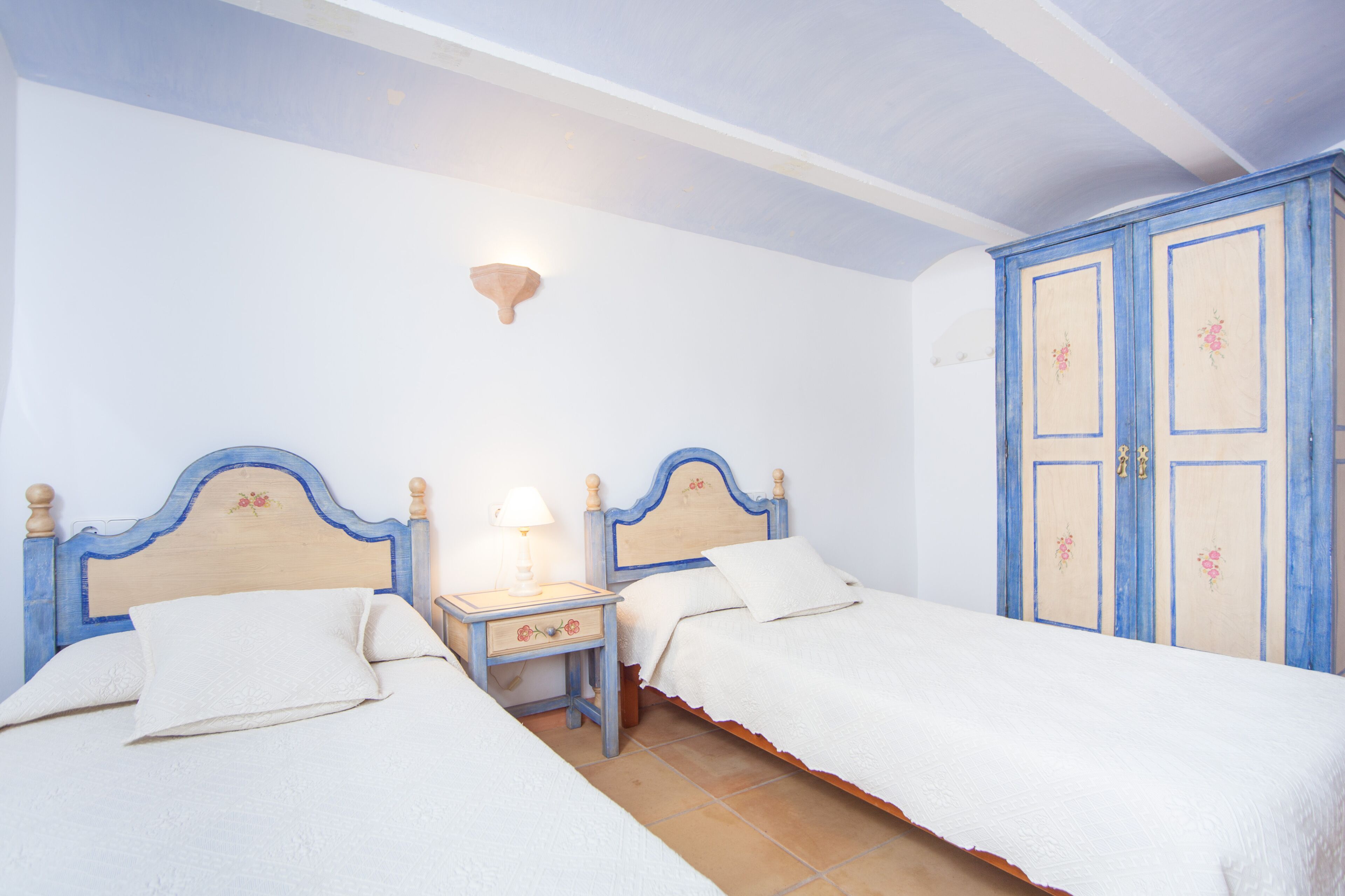 Una camera da letto con due letti, un comodino con una lampada e un armadio.