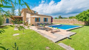 Une villa dotée d’une piscine, d’un espace salon extérieur et d’un mur en pierre.
