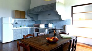 A kitchen with a dining table, chairs, a microwave, a stove, and a refrigerator.