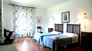 A room with two beds, a wooden headboard, a nightstand, a lamp, and a framed picture on the wall.