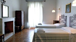 A room with two beds, a fireplace, a mirror, and a window with curtains.