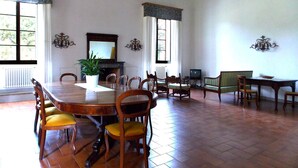 Un comedor amplio con una gran mesa de madera y sillas, una planta en maceta y una chimenea.