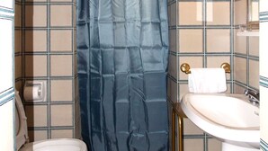 Un baño con inodoro, lavamanos y cortina de ducha.
