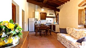 A cozy kitchen with wooden beams, a dining area with a floral sofa, and a vase of yellow flowers on a wooden table. - Residence in Carbonile with 2 bedrooms sleeps 6 (Carbonile)