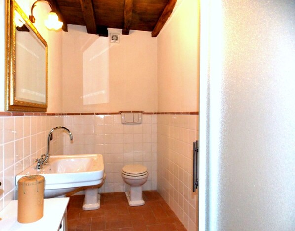Un baño con lavamanos, inodoro y espejo.