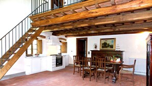 Une cuisine avec coin repas, un escalier en bois et une vue sur l’extérieur.