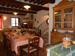 A dining area with a wooden table set for a meal, a staircase, and a wooden cabinet with glass doors.
