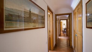Ein Korridor mit Holztüren und gerahmten historischen Gemälden an den Wänden.