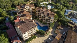 An aerial view of a hotel with multiple buildings, a central swimming pool, and surrounding greenery. - Sunrise 33- 3 Bedroom Poolside Condo (Tamarindo)