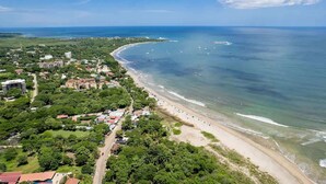An aerial view of a coastal area with a beach, buildings, and boats. - Sunrise 33- 3 Bedroom Poolside Condo (Tamarindo)