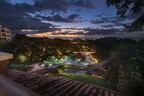 Un complexe hôtelier doté d’une piscine, d’une végétation luxuriante et offrant une vue sur l’océan au crépuscule.