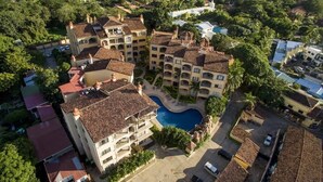 An aerial view of a hotel with multiple buildings, a central swimming pool, and surrounding greenery. - Sunrise 23- 2 Bedroom Ocean View Condo (Tamarindo)