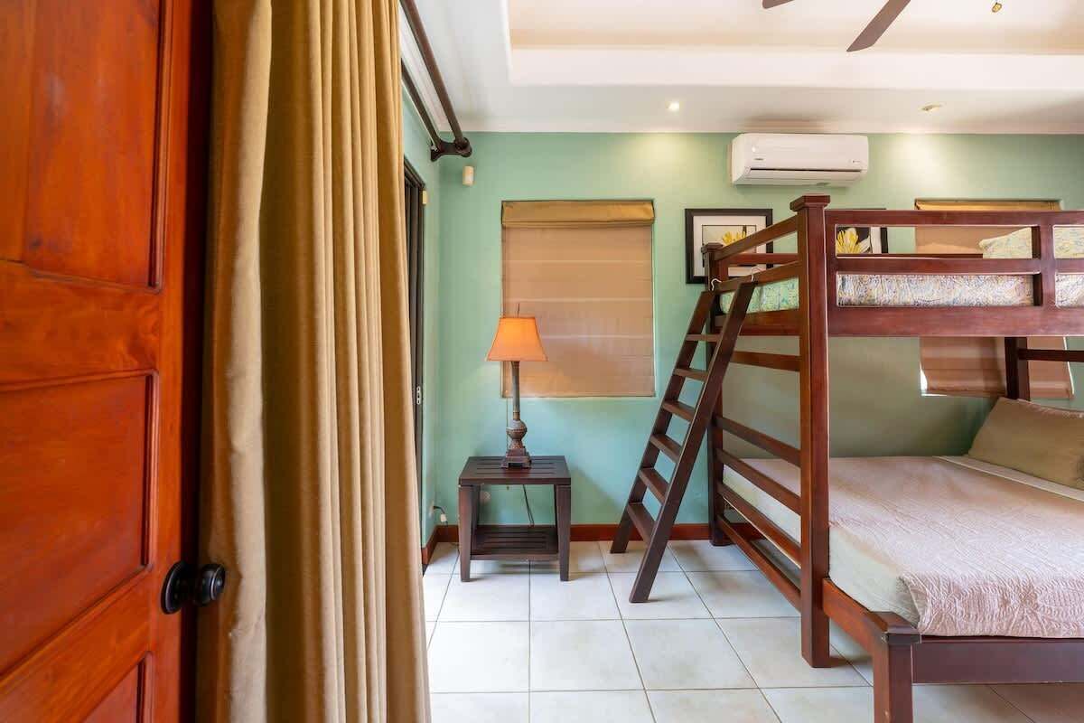 A room with bunk beds, a small table with a lamp, and a door.