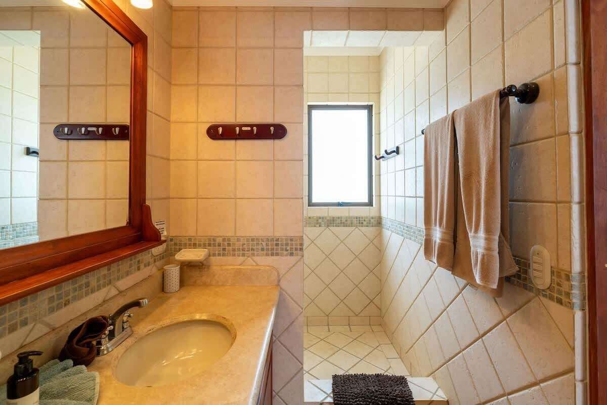 A bathroom with a large mirror, a sink, and a shower area.
