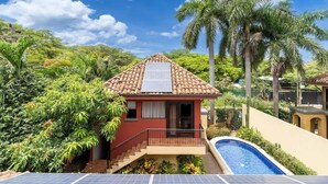 A house with a tiled roof, a swimming pool, and solar panels. - Jade Coast #3- Private 5 Bedroom Villa (Tamarindo)