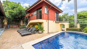 A two-story house with a swimming pool, a balcony, and a garden area with lounge chairs. - Jade Coast #3- Private 5 Bedroom Villa (Tamarindo)