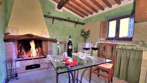 A cozy dining area with a fireplace, a table set for two, and a wine bottle. - Private Villa with private pool, hot tub, WIFI, A/C, TV, patio, pets allowed, panoramic view (Montepulciano)
