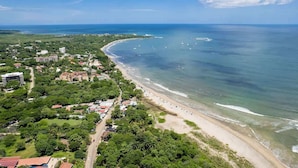 An aerial view of a coastal area with a beach, buildings, and boats.