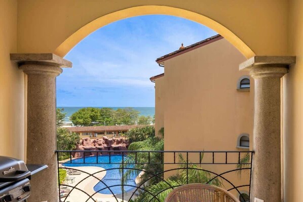Un balcon avec vue sur une piscine et l’océan.