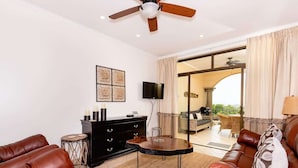 A living room with leather sofas, a black cabinet, a round table, and a ceiling fan.