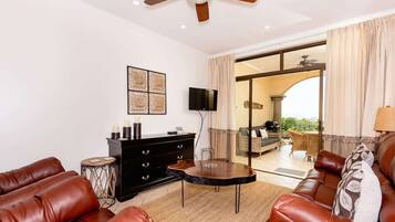A living room with leather sofas, a black cabinet, a round table, and a ceiling fan.