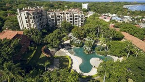 Ein Resort mit einem großen Gebäude, einem Schwimmbad und üppiger Vegetation.