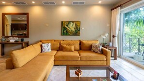 A living room with a large sofa, a coffee table, and a painting on the wall. - Matapalo 302- 2 Bedroom Condo at Tamarindo (Tamarindo)