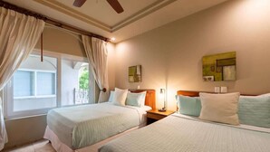 A hotel room with two beds, a window with curtains, a ceiling fan, and artwork on the walls. - Matapalo 302- 2 Bedroom Condo at Tamarindo (Tamarindo)