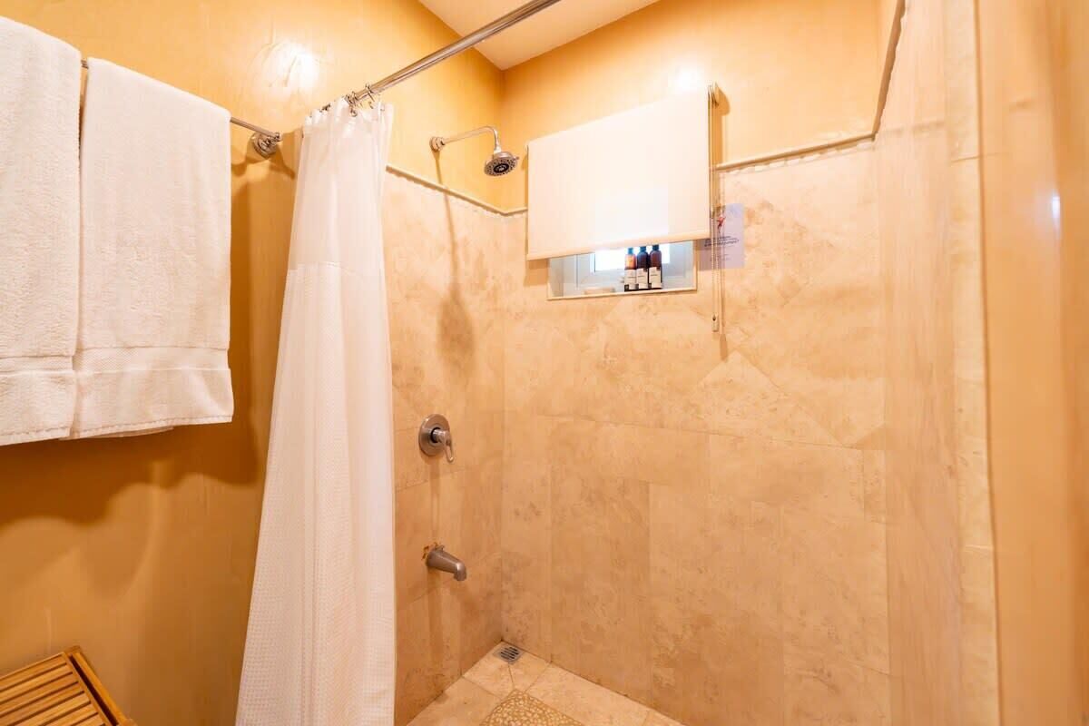 A shower area with a glass enclosure, a towel rack, and a small shelf with toiletries.
