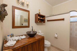 A bathroom with a wooden vanity, a large mirror, a sink with a bowl, a toilet, and a towel rack.