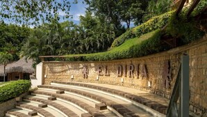 An outdoor amphitheater with stone steps and a stone wall with the text "A FIESTA."
