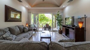 A living room with a sofa, coffee table, TV, and a ceiling fan.