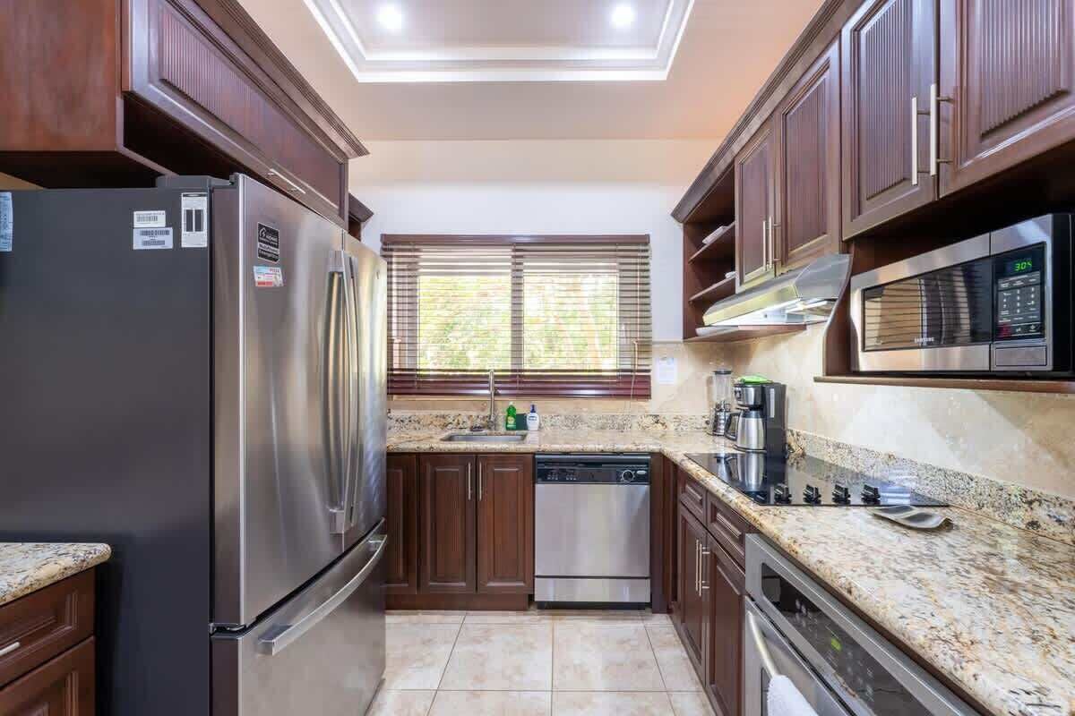 A kitchen with dark wooden cabinets, stainless steel appliances, and a granite countertop.