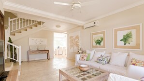 Un vaste espace de vie comprenant un escalier blanc, un coin repas et un ventilateur de plafond.