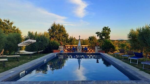 Una piscina con lettini e un gazebo.