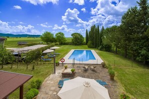 A swimming pool with a surrounding patio area, including lounge chairs and umbrellas.