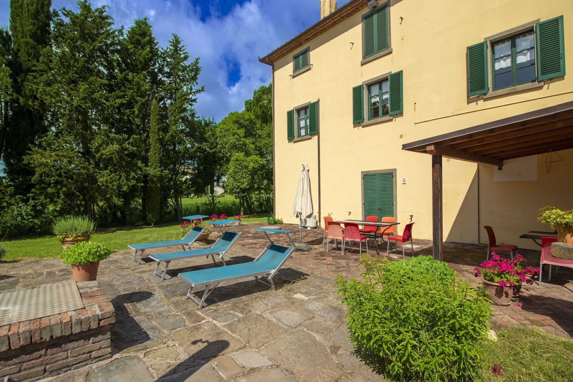 A building with a patio area featuring lounge chairs, a table, and potted plants.