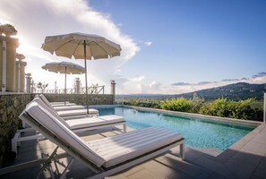 A pool area with lounge chairs and umbrellas, stone walls, and a view of distant hills. - Wonderful private villa with WIFI, private pool, A/C, TV, terrace, panoramic view, close to Cortona (Il Castagno)