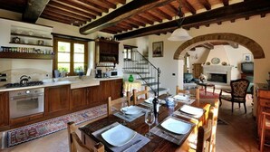 A rustic kitchen with wooden cabinets, a gas stove, and a dining area with a table set for two.