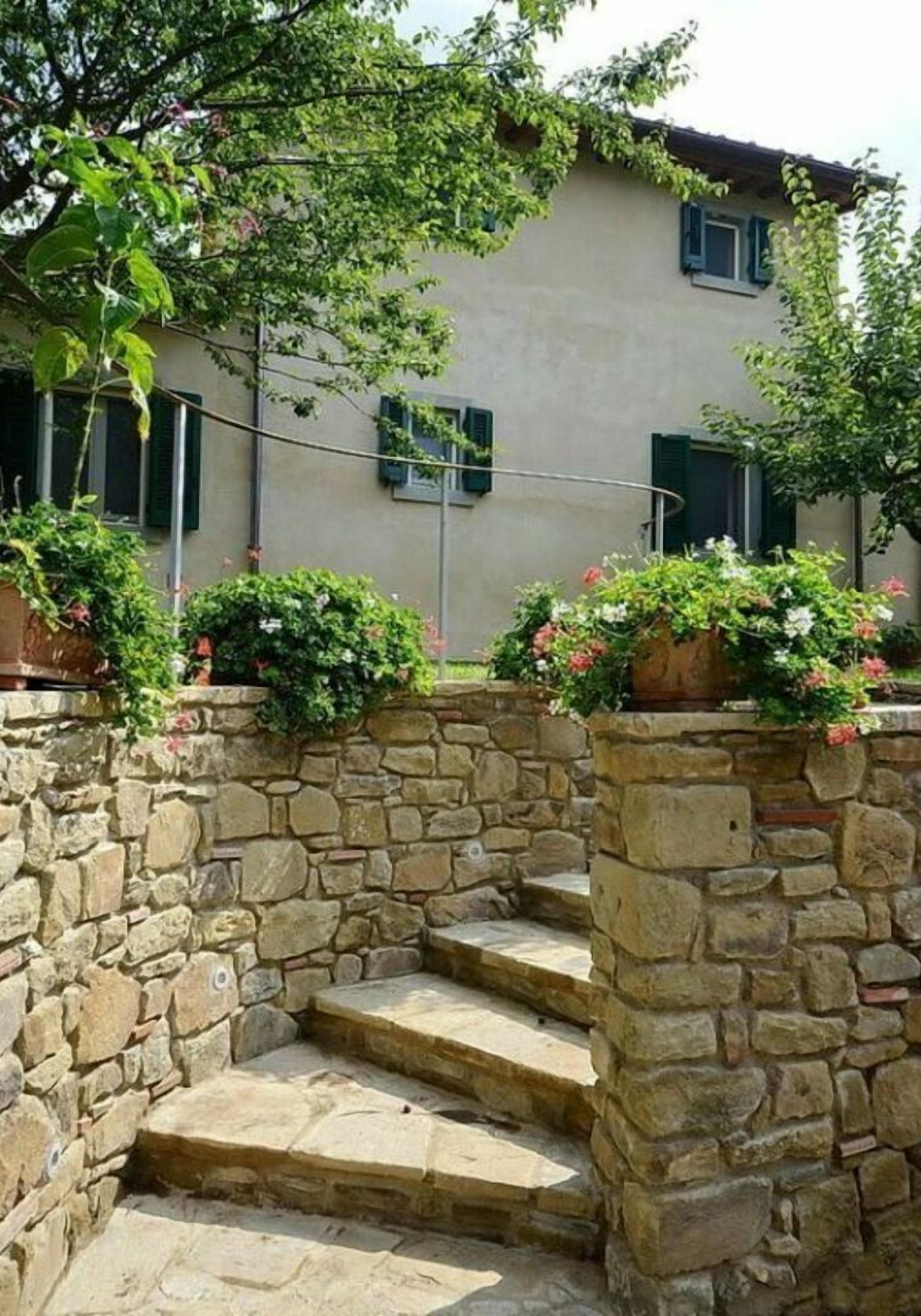 Una escalera de piedra que lleva a un edificio con pared de piedra y plantas en macetas.