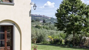 A building with a large arched entrance, a well-maintained lawn, and a view of a distant cityscape. - Wonderful private villa with private pool, WIFI, A/C, TV, patio, panoramic view, close to Cortona (Cegliolo)