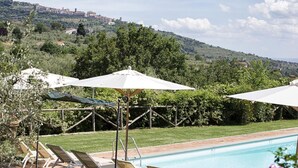 A poolside area with lounge chairs and umbrellas, overlooking a hillside with buildings. - Wonderful private villa with private pool, WIFI, A/C, TV, patio, panoramic view, close to Cortona (Cegliolo)