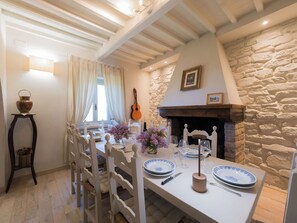 A dining area with a stone wall, a fireplace, and a guitar.