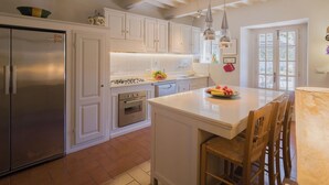A kitchen with white cabinets, stainless steel appliances, a central island, and pendant lighting.